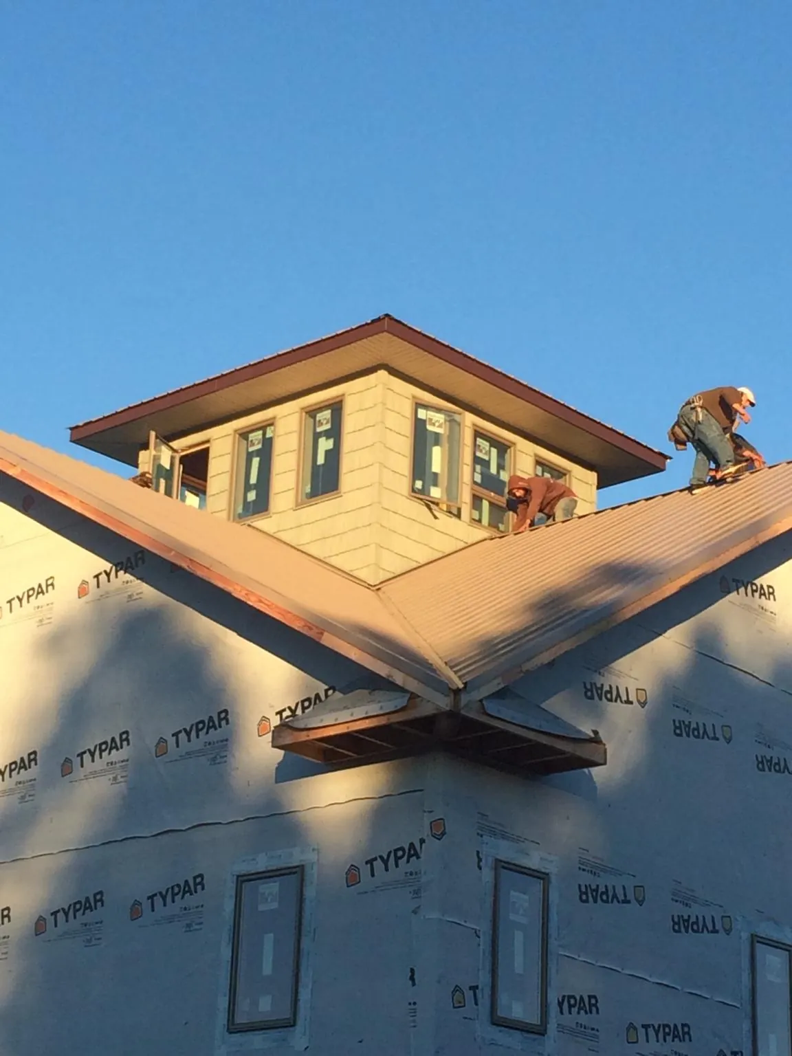 Roofers working around a rooftop cupola on a new metal roof at sunset — Roof Waterproofing in Osseo by Roofing Brothers